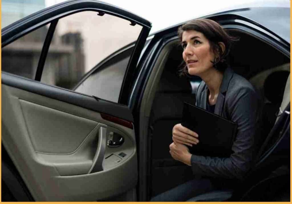 Boston Luxury Chauffeur Service image featuring a dark car interior and a professional passenger holding a folder in the back seat, Concord MA area