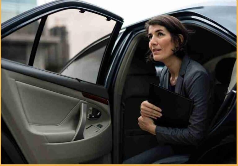 Boston Luxury Chauffeur Service image featuring a dark car interior and a professional passenger holding a folder in the back seat, Concord MA area