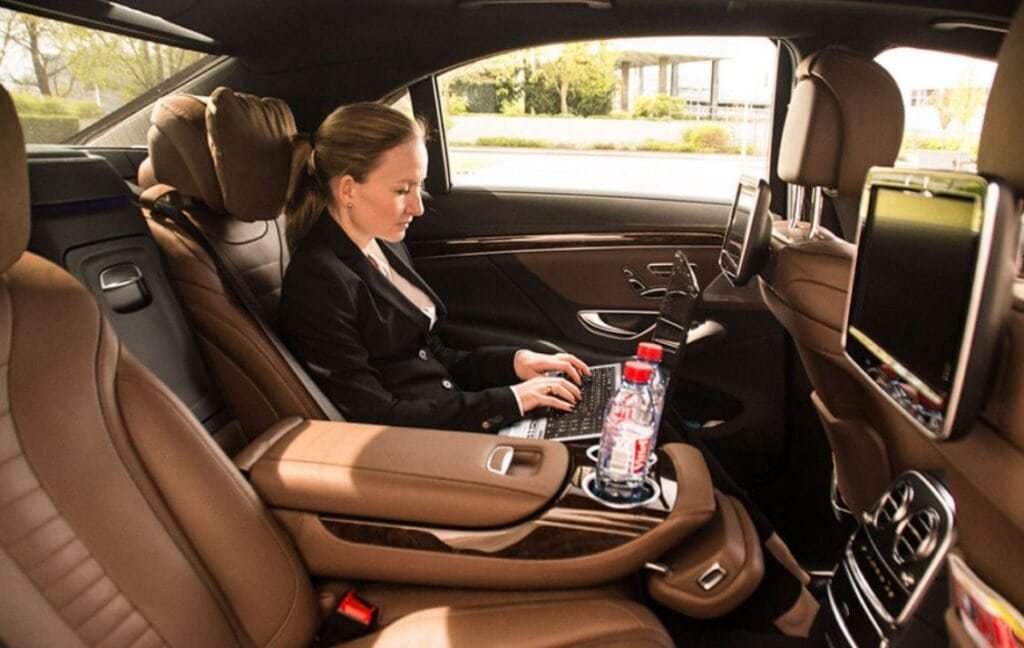 Passenger enjoying a comfortable ride in the back seat of a luxury car during a city-to-city transfer