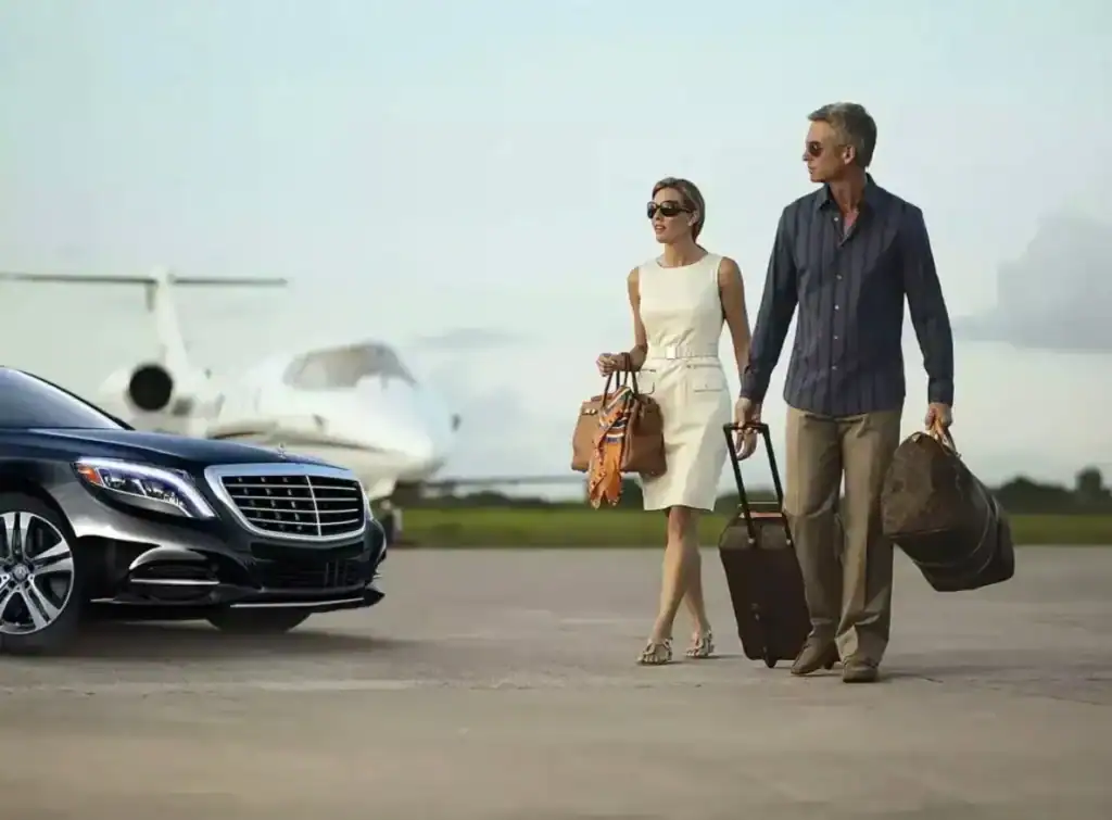Couple with rolling luggage beside a black luxury sedan on the airport tarmac, wearing sunglasses, conveying premium chauffeur service and seamless airport transfers.