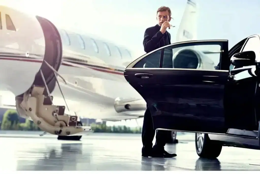 Professional chauffeur standing beside a black luxury sedan near a private jet for Weston Car Service – Airport Transfers