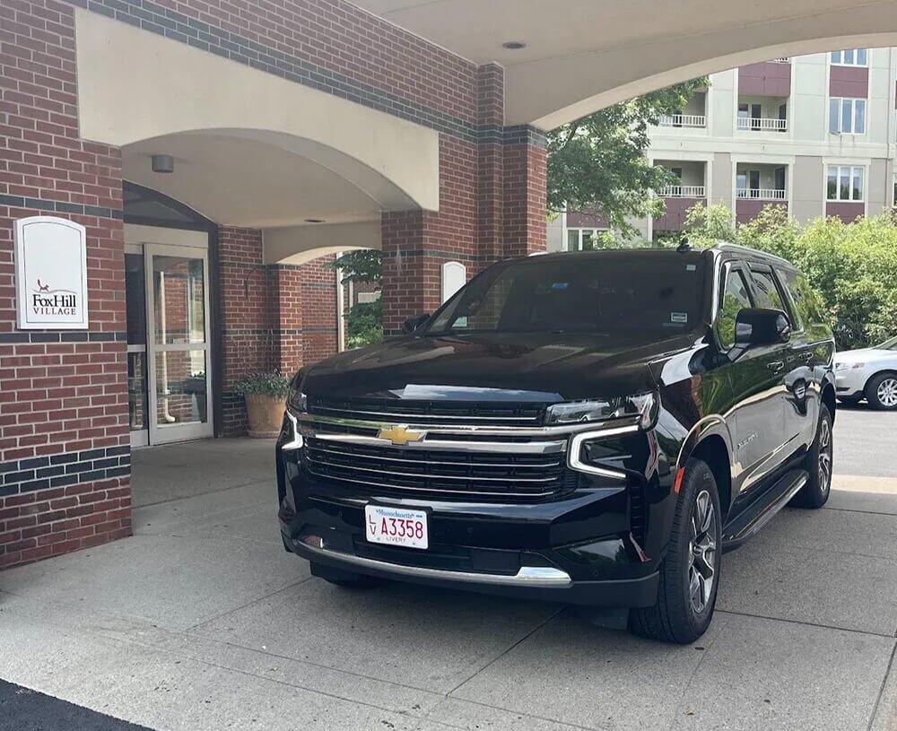 Black luxury SUV parked under a covered valet area, ready for professional chauffeur service