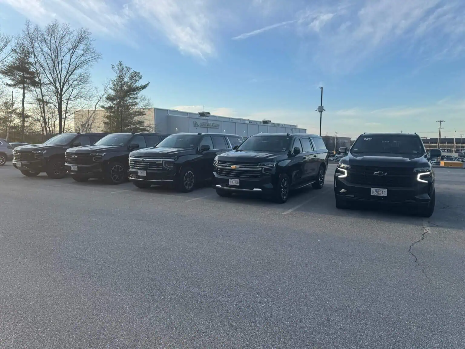 Boston Luxury Chauffeur fleet of black Chevrolet Suburbans parked in a row under a blue sky