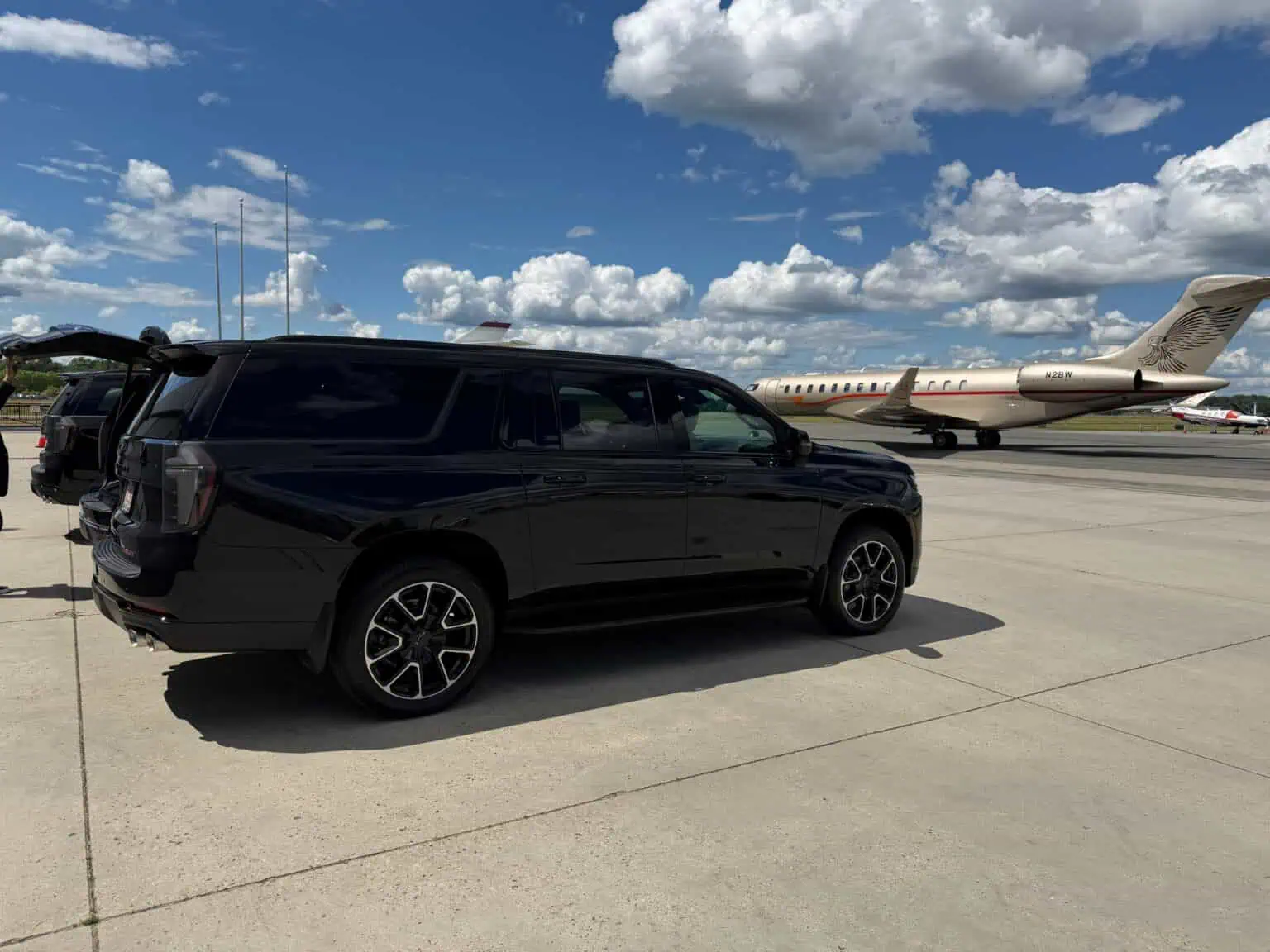 Boston Luxury Chauffeur black full-size SUV on an airfield apron beside a private jet