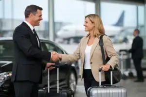 Businesswoman and chauffeur shaking hands at Logan Airport.